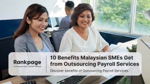 two-asian-female-colleagues-sitting-at-office-desk-with-laptop-helping each-other-smiling