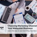 Two employees sit at a desk discussing marketing channels.