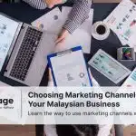 Two employees sit at a desk discussing marketing channels.