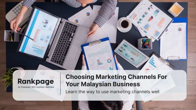 Two employees sit at a desk discussing marketing channels.