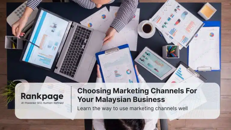 Two employees sit at a desk discussing marketing channels.