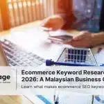 A man typing on a laptop to conduct ecommerce research, with a model of a shopping cart on his desk nearby.