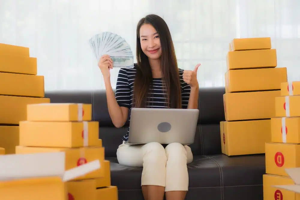 Ecommerce businesswoman holding money and surrounded by boxes of products
